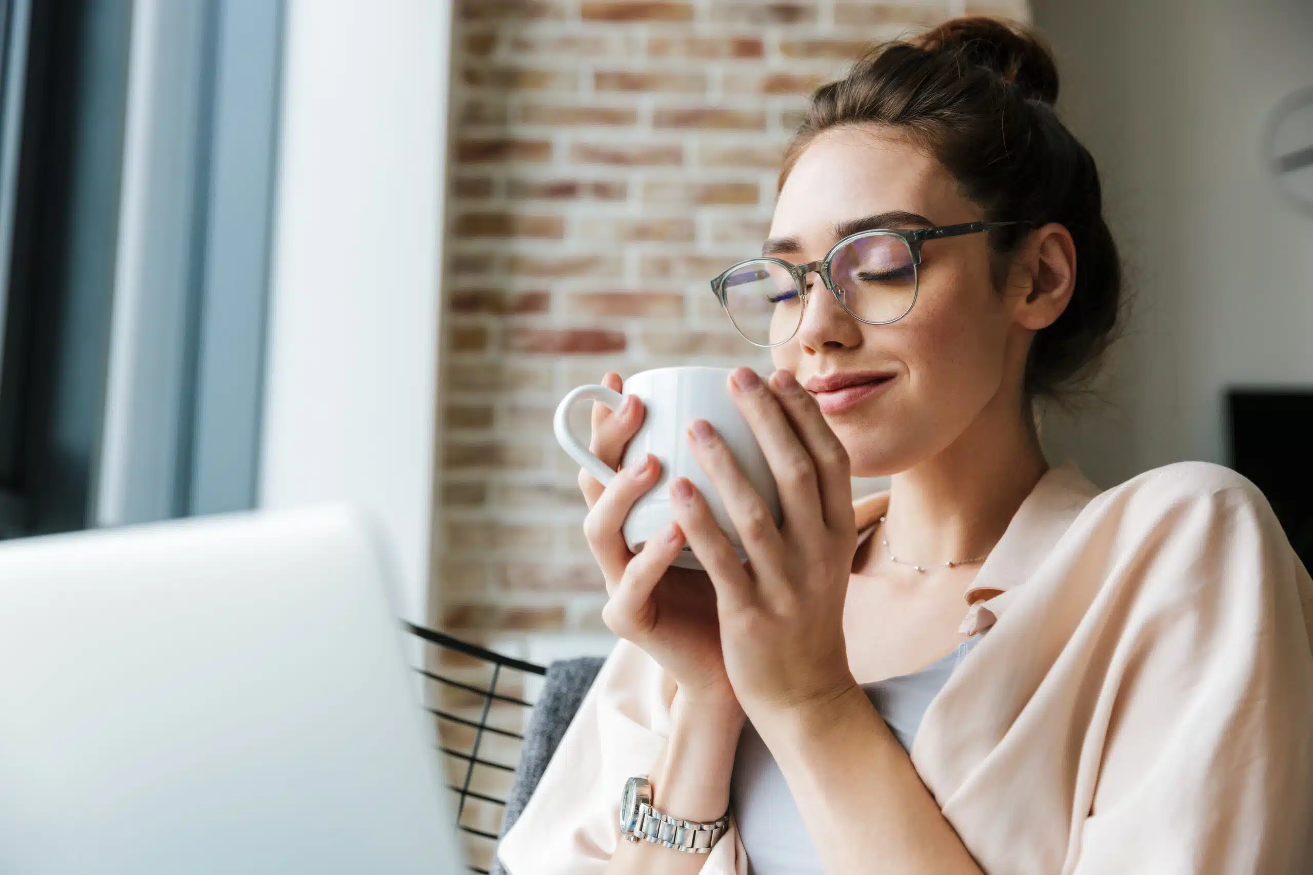 Image of woman working with laptop and drinking coffee while sitting