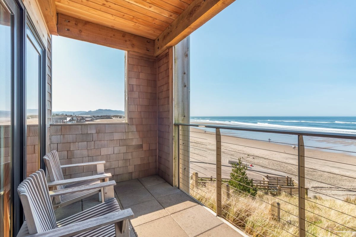 A peaceful oceanfront balcony with two chairs overlooking the beach, representing the serene and restorative setting of RESET Retreats by Ancorio.