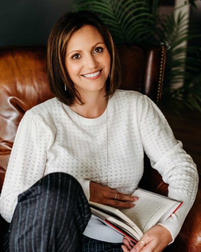 Dr. Stephanie Grunewald, Women's Empowerment Coach, reading book, smiling.